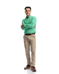 Naklejka premium Happy young man standing with arms crossed