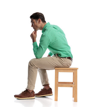 Side view of thoughtful casual man sitting on stool