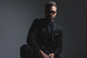 Obraz premium Dramatic fashion man in black suit man sitting