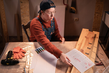 woman in eyeglasses reviews plans in carpentry workshop working overworked overtime