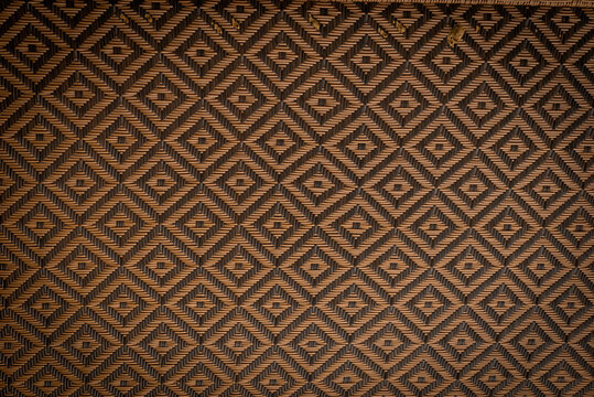 Dark woven rattan texture with geometric diamond pattern and natural material detail background
