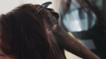 salon caucasian stylist clipping and sectioning hair in preparation for styling, metal clips holding layers, gloved hands arranging neat parts, calm client posture, focused salon environment
