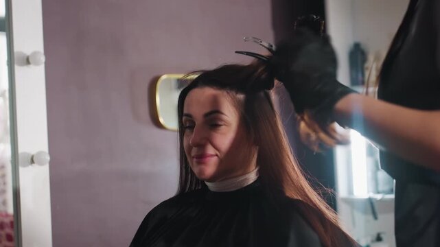 hair styling process, color and volume preparation techniques, stylist lifts hair near roots with clips, salon professional carefully sections hair close to roots using clips and combs