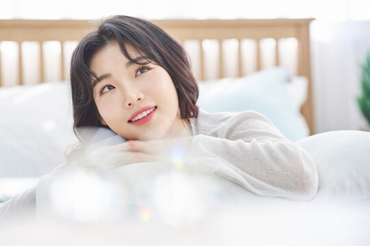 Relaxed Asian woman smiling softly in bed