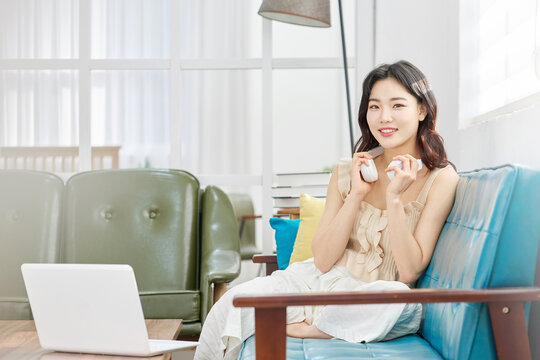 Relaxed young woman with wireless headphones on cozy sofa near laptop