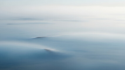 Obraz premium Ethereal calm water surface with mist and gentle waves, tranquil and peaceful ambiance, copy space