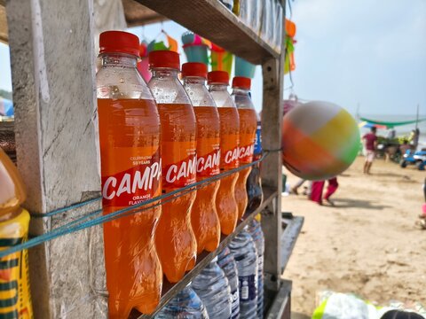 Beach stall displaying Campa orange cola and soda bottles backed by Ambani&rsquo;s Reliance revival, showcasing juice beverages and shifting market competition, highlighting business profit and loss.