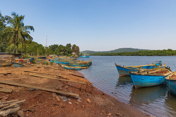 River with lush green river bank and sand mining boats at Goa India