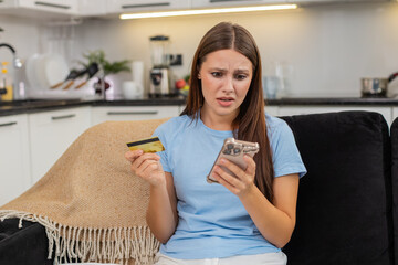 Young woman at home tries payment on smartphone with credit card sees alert for low funds and...