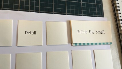 White Note Cards on Green Mat with Words Detail and Refine the Small Representing Organization and Planning Concepts