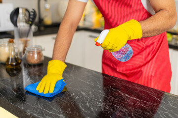 Arabian man wipes kitchen counter with cleaner and microfiber cloth removing grease for hygiene and...