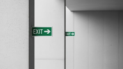 Green exit sign with arrow pointing to the right in a modern building hallway.