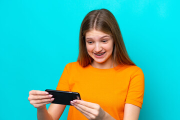 Naklejka premium Teenager Russian girl isolated on blue background playing with the mobile phone