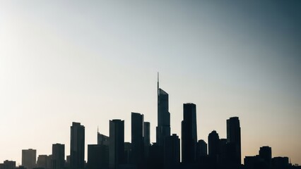 Silhouette of a modern city skyline against a hazy sky at dawn.