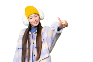 Young Asian woman wearing winter muffs over isolated chroma key background giving a thumbs up gesture