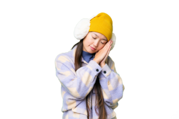Young Asian woman wearing winter muffs over isolated chroma key background making sleep gesture in dorable expression