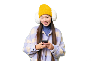 Young Asian woman wearing winter muffs over isolated chroma key background sending a message with the mobile