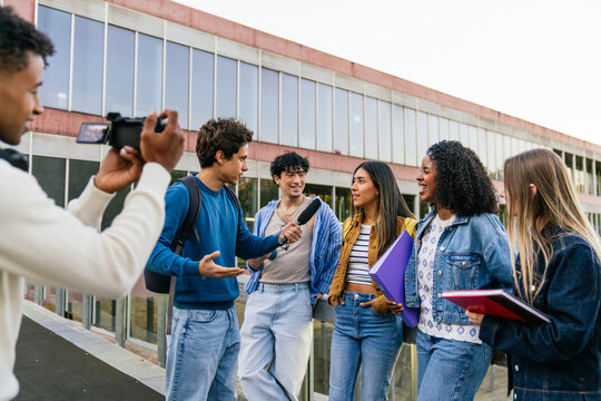 Journalism students filming and interviewing young adults about education and campus life for a news report