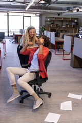Diverse coworkers celebrating milestone in open-plan office with smartphone and computer monitors