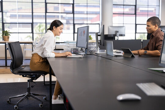 Diverse coworkers typing on laptop and writing notebook at desk in office, copy space - Powered by Adobe
