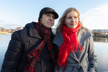 Couple enjoys a stroll by the riverside on a clear winter day wearing warm clothing