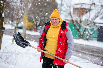 Man in winter clothing shoveling snow in a neighborhood during a snowstorm