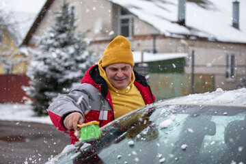 Man clearing snow from car windshield during winter storm in residential area