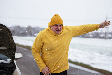 Winter roadside emergency with a man in yellow hoodie struggling against snow