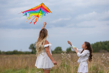 Colorful kite flying in a field with a mother and daughter enjoying a sunny afternoon outdoors