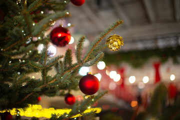 Decorated Christmas tree with red ornaments and warm festive lights in a cozy indoor space