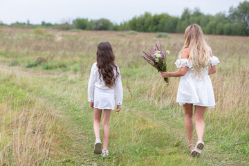 Walking on a grassy path with flowers in hand during a serene afternoon in a countryside setting