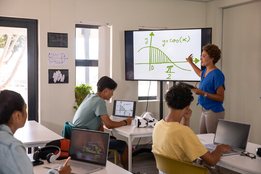African american female instructor pointing at cosine curve on classroom display screen