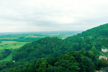 Fototapeta premium Panoramic view of green hills and forests from the Štramberk lookout tower. Picturesque summer landscape of Beskydy mountains under cloud, natural horizon, ecology and tourism in the Czech Republic.