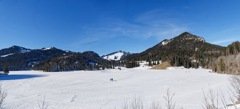 Spitzingsee-Tegernsee ski area in Bavarian Alps. Hiking and cross-country skiing on the frozen lake facing the snow-capped Becherspitz massifs and Bodenschneid towards Untere Firstalm
