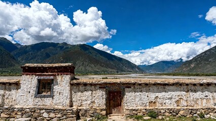 Stone wall structure in a mountain valley with clear blue sky and distant peaks