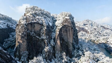 Snow-covered rock formations in a mountainous landscape with forest and river below