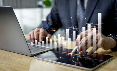 A financial adviser analyzes market diagrams on a tablet, viewing charts and graphs with technology icons to express economic growth, future trends, and success in digital finance strategy.