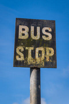 old bus stop road traffic sign on pole against blue sky