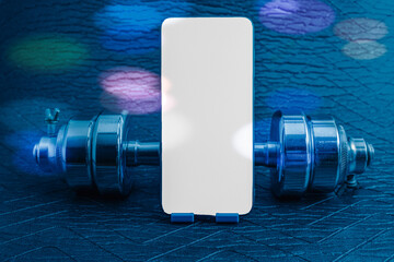 Smartphone mock up screen on a stand between chrome dumbbells, symbolizing digital fitness
