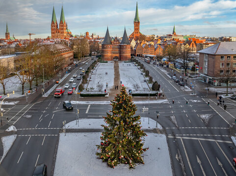 Aerial winter view of the historic Holstentor in L&uuml;beck, Germany with  large decorated Christmas tree centered in the foreground.
