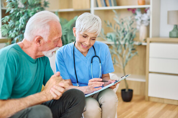 Portrait of a senior doctor or nurse caregiver talking consultation with senior man at home or...