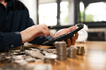 Person using a calculator while counting cash and coins on a desk, representing budgeting, personal finance management, expenses, savings, and financial planning.