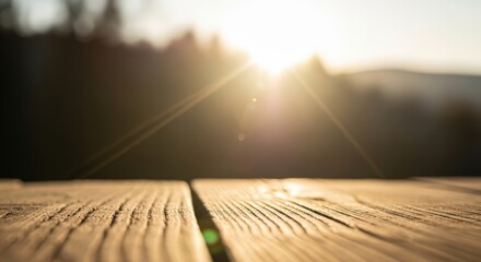Wooden table surface in foreground with bokeh blurred mountain and tree landscape at sunset. Golden sun rays breaking through serene nature scene. Outdoor background concept for product photography