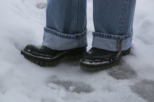 Danger of slipping. Person in chunky platform leather boots walking on snowy icey road