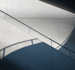 Title: Minimalist Modern Architecture Abstract with Curved Ramp Handrail and Dramatic Geometric Shadow on Concrete Surface