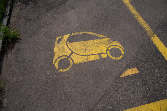 Yellow microcar parking stencil on asphalt in Z&uuml;rich - close-up top view of EV-designated compact parking bay