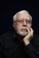 Obraz premium Older man with white beard sitting alone thinking deeply in a dark room