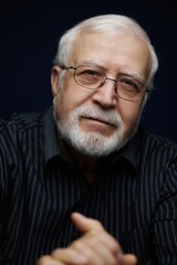 Obraz premium Senior man with glasses smiling and looking directly at the camera in indoor setting