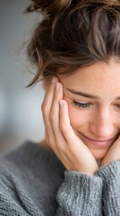 Fototapeta premium Young woman finding emotional relief, smiling with eyes closed, hands touching face in comfort