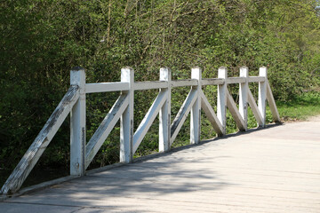 Kleine Br&uuml;cke &uuml;ber einen Teich mit einem wei&szlig;en Holzgel&auml;nder